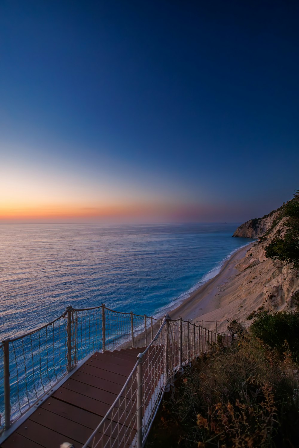 a wooden walkway leading to the beach at sunset