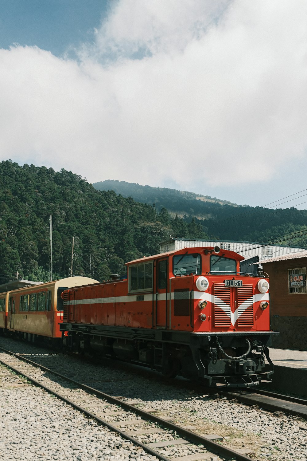 a red train traveling down train tracks next to a forest