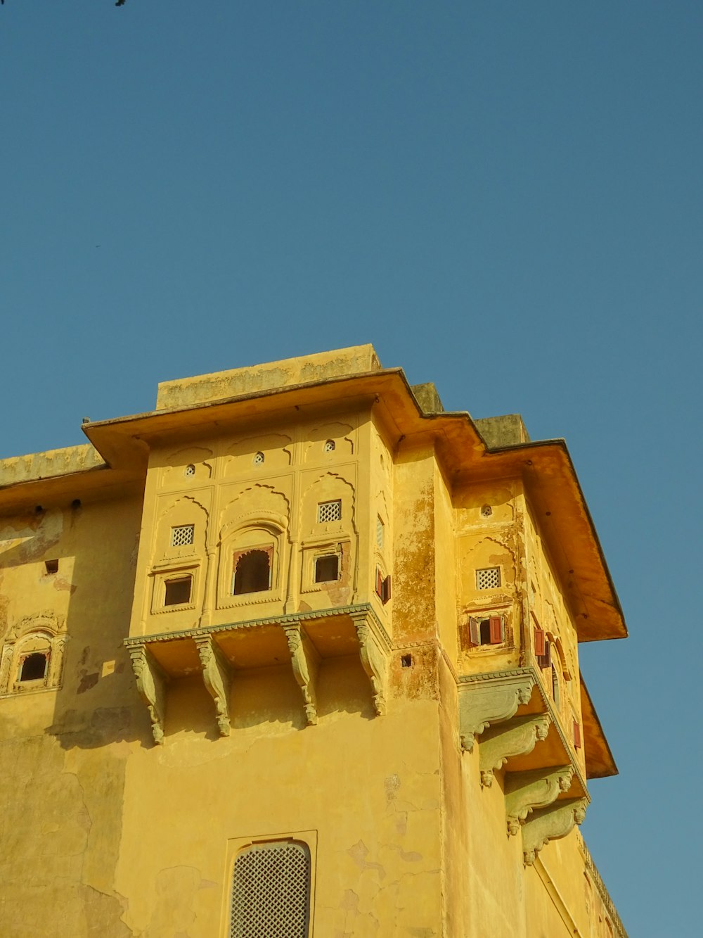 a yellow building with a bird flying in the sky