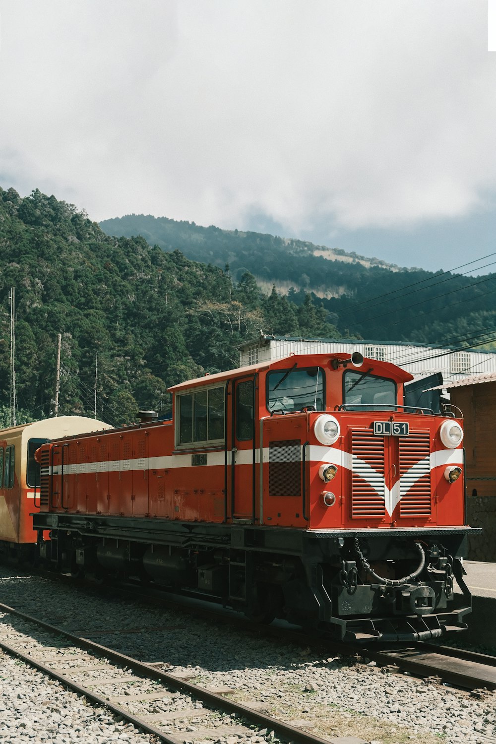 a red train traveling down train tracks next to a forest