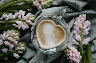 a cup of coffee sitting on top of a table next to flowers