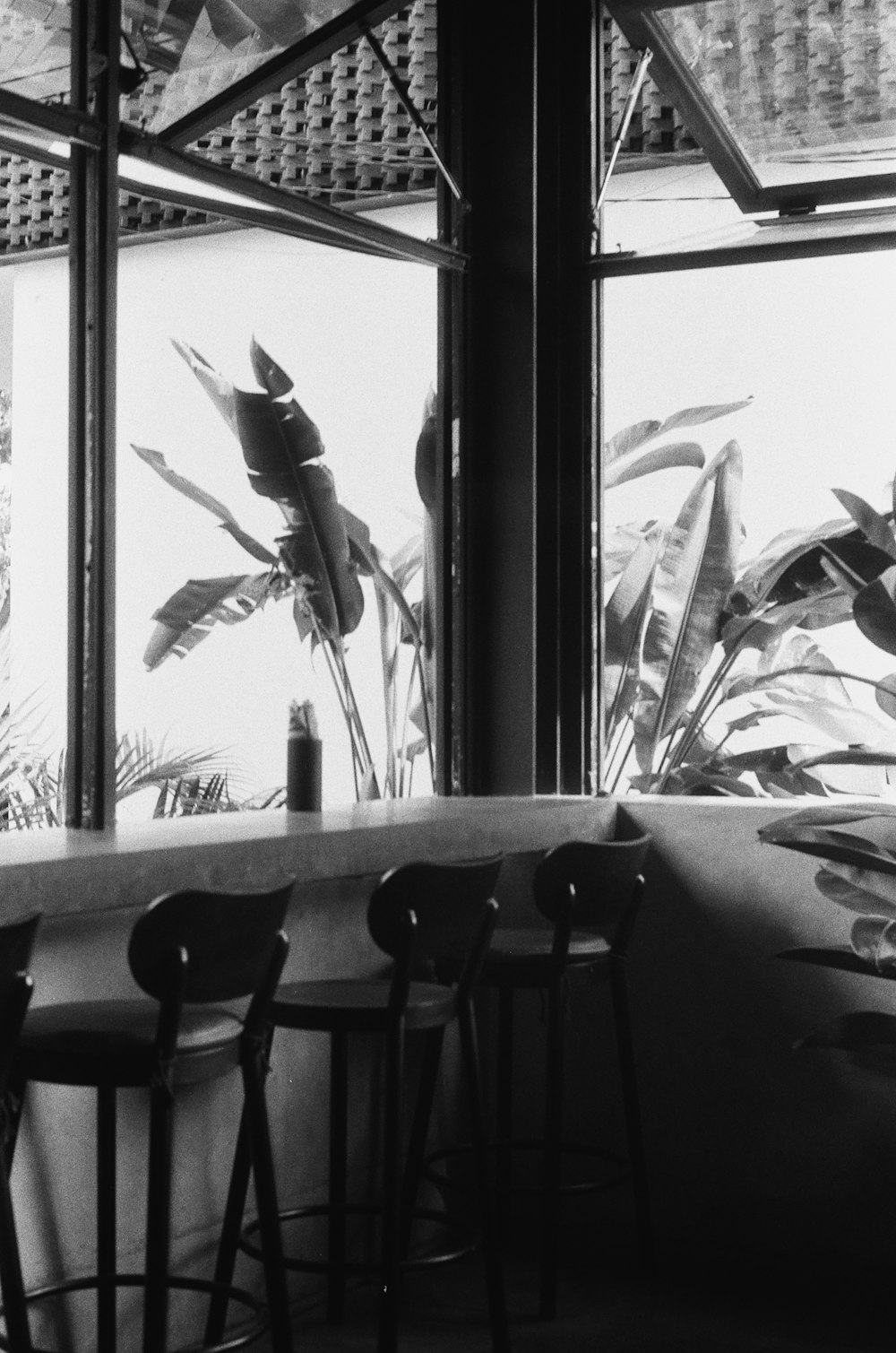 a black and white photo of a bar with three stools