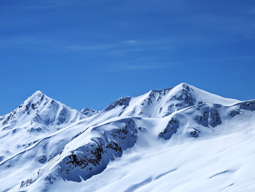 a snow covered mountain range under a blue sky