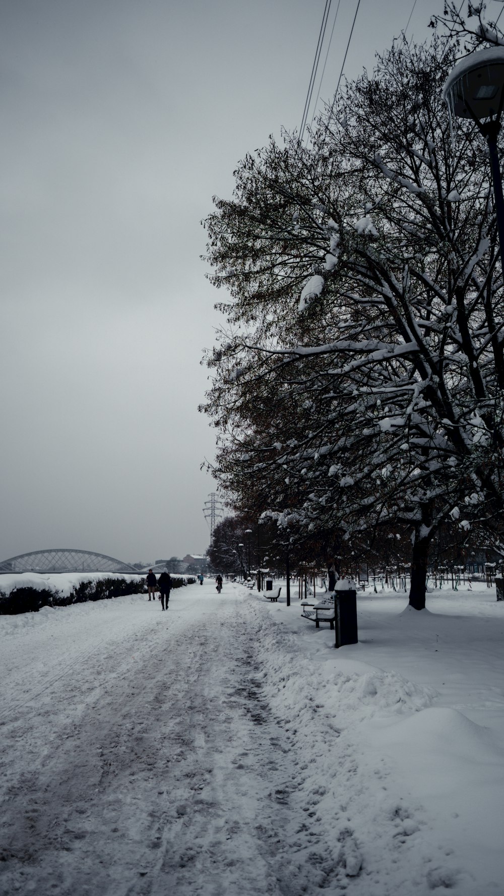 a snow covered road with a bridge in the background