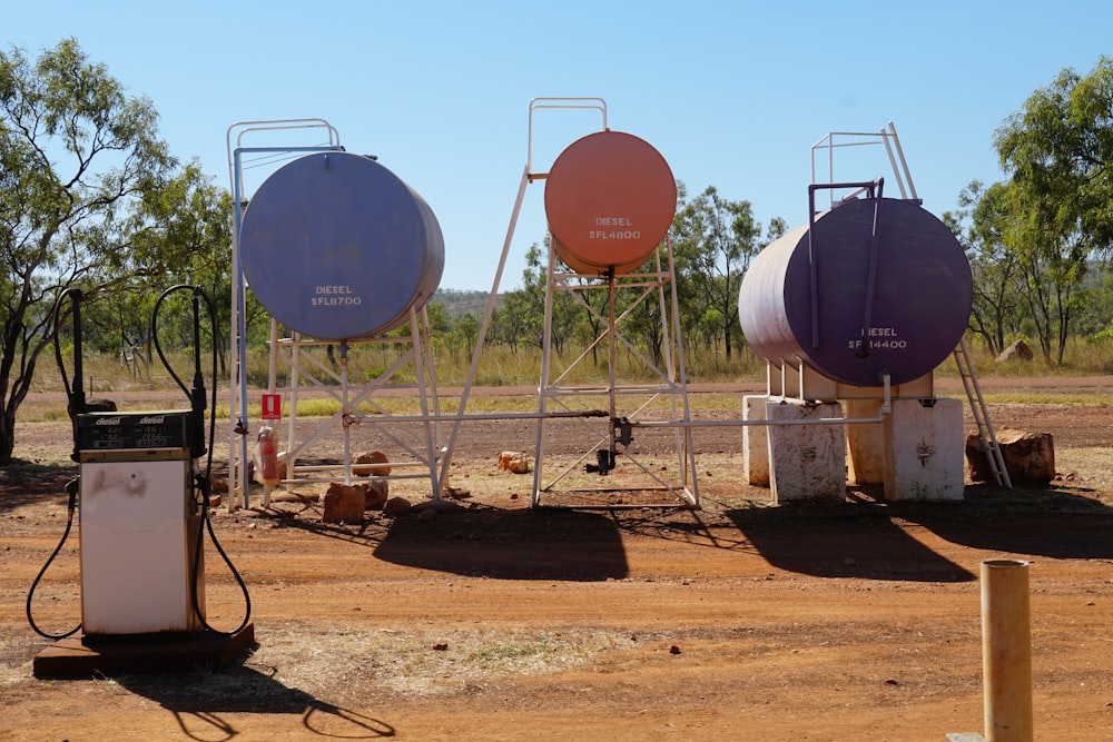a group of gas tanks sitting on top of a dirt field