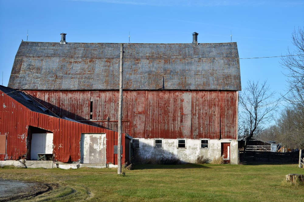 an old red barn sits in the middle of a field