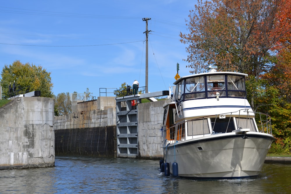 a white boat traveling down a river next to a bridge