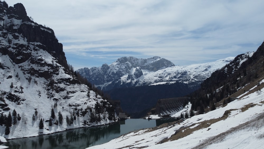 a snowy mountain landscape with a lake in the foreground