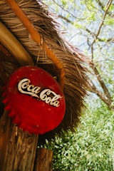 a coca cola sign hanging from a thatched roof