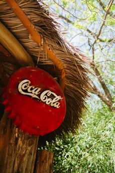 a coca cola sign hanging from a thatched roof