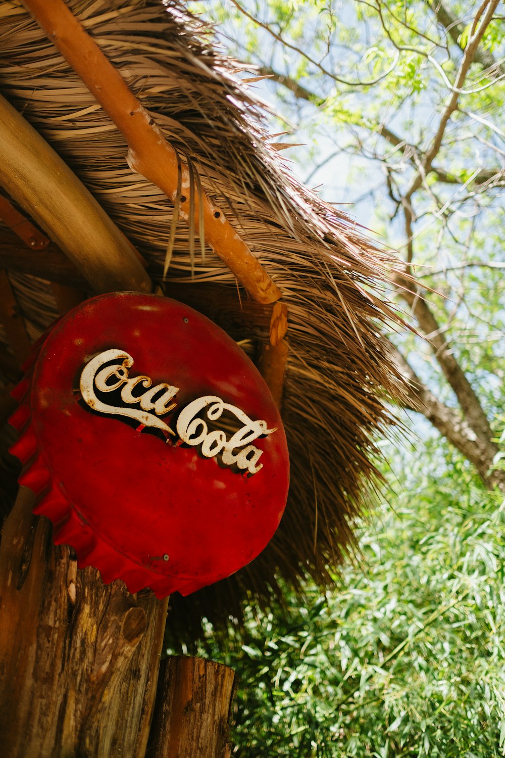 a coca cola sign hanging from a thatched roof