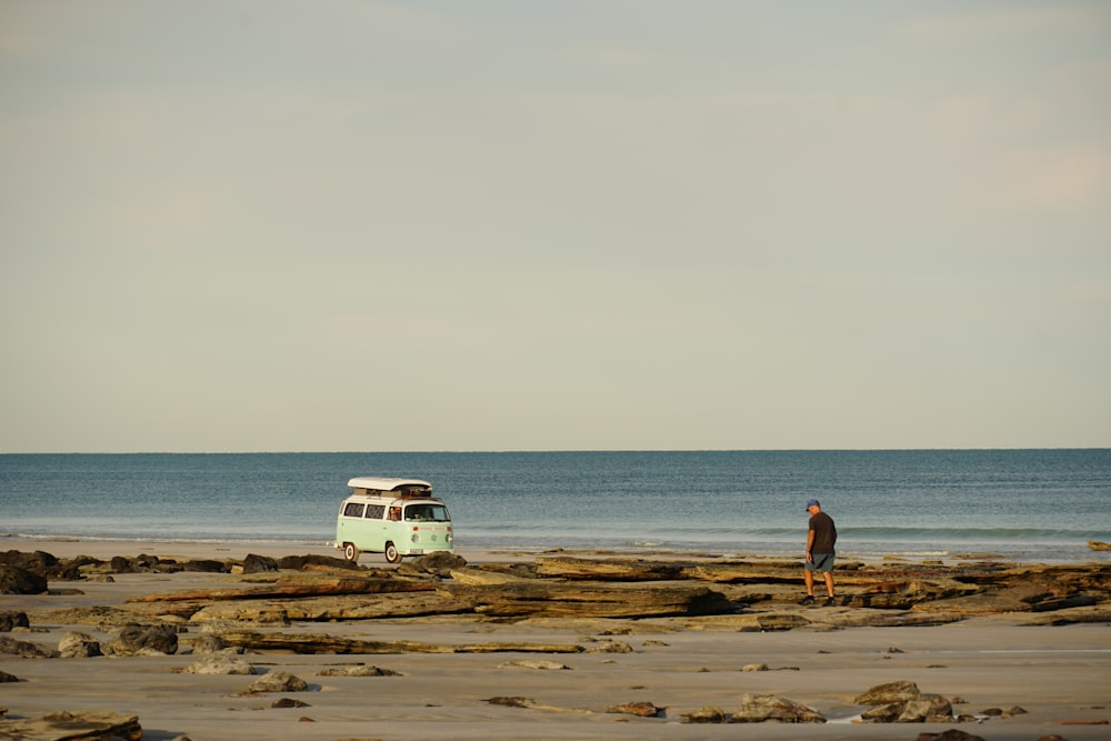 a person standing on a beach next to a van