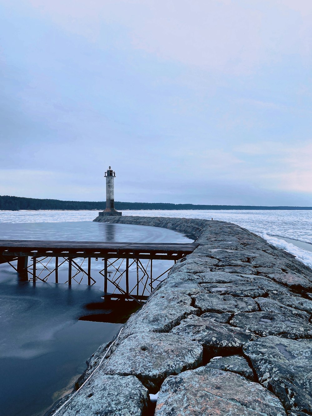 a light house sitting on top of a pier next to the ocean