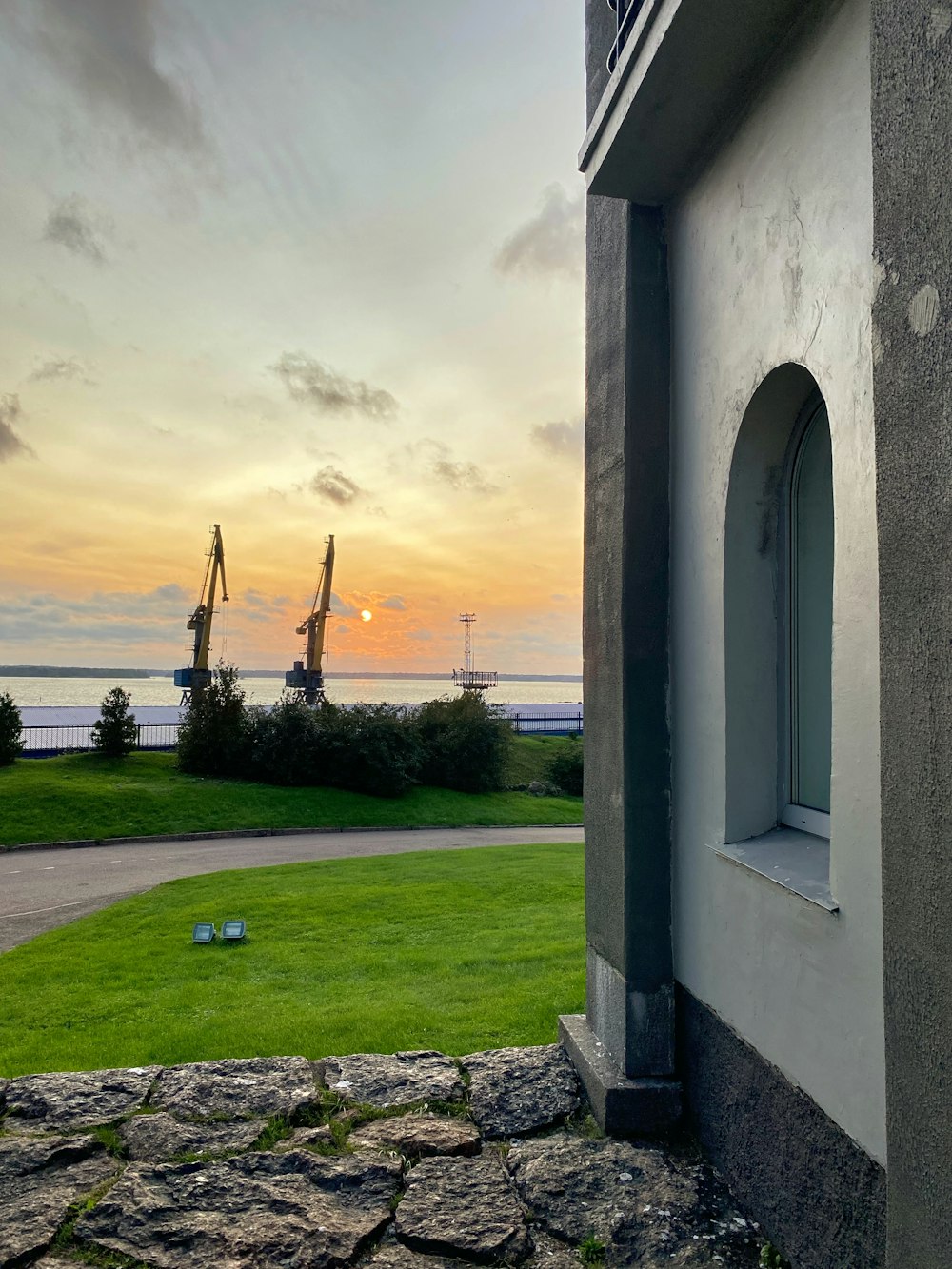 the sun is setting over the ocean from a house