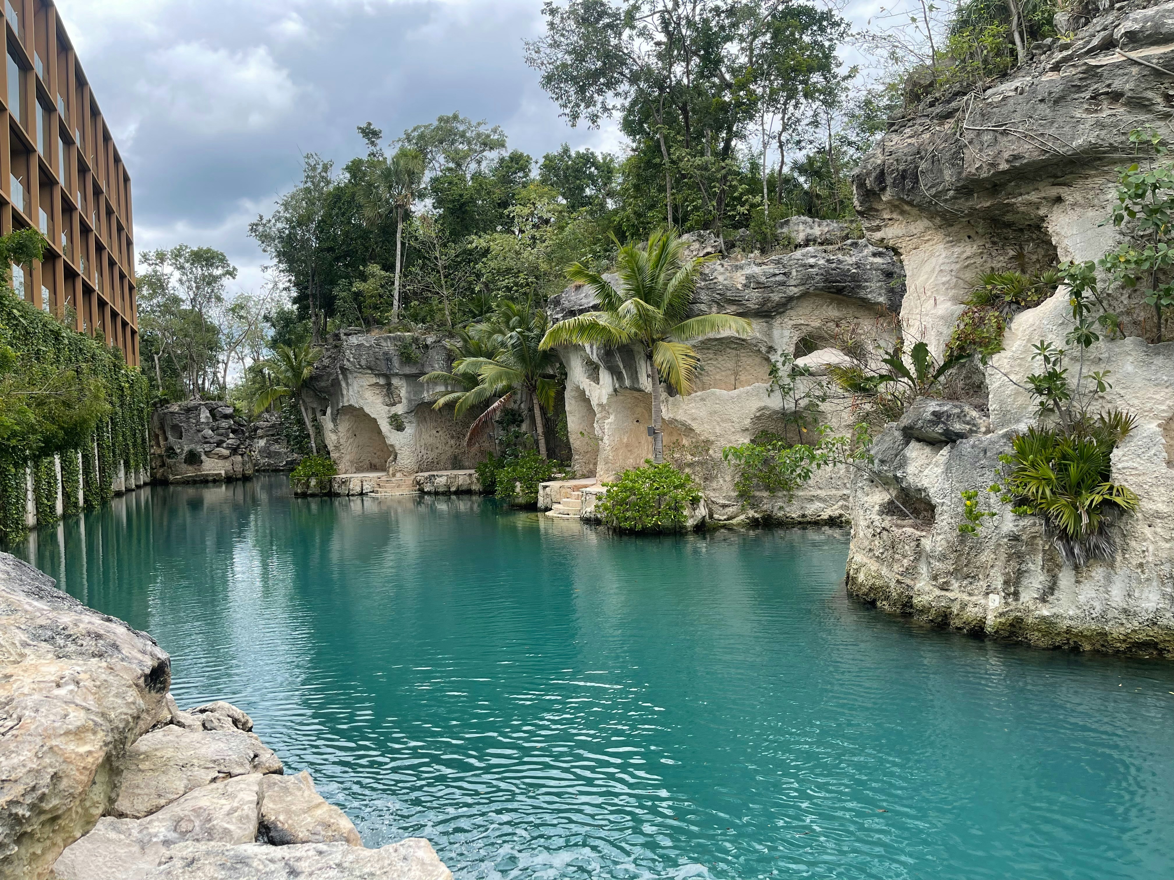 a large body of water surrounded by a lush green forest, Xcaret