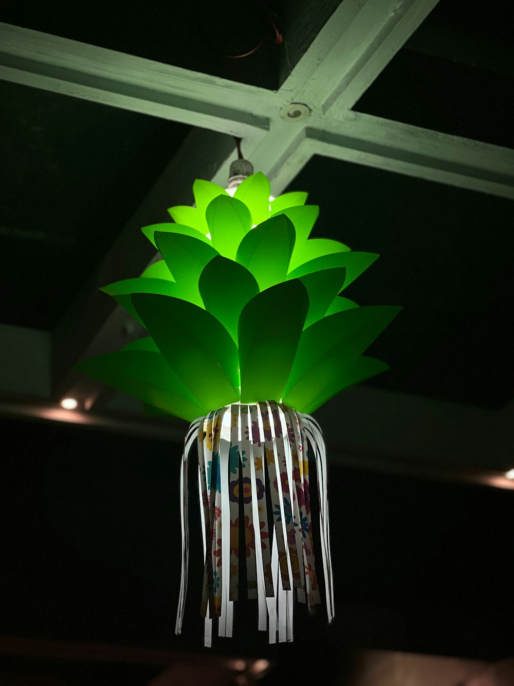 a green paper flower hanging from a ceiling