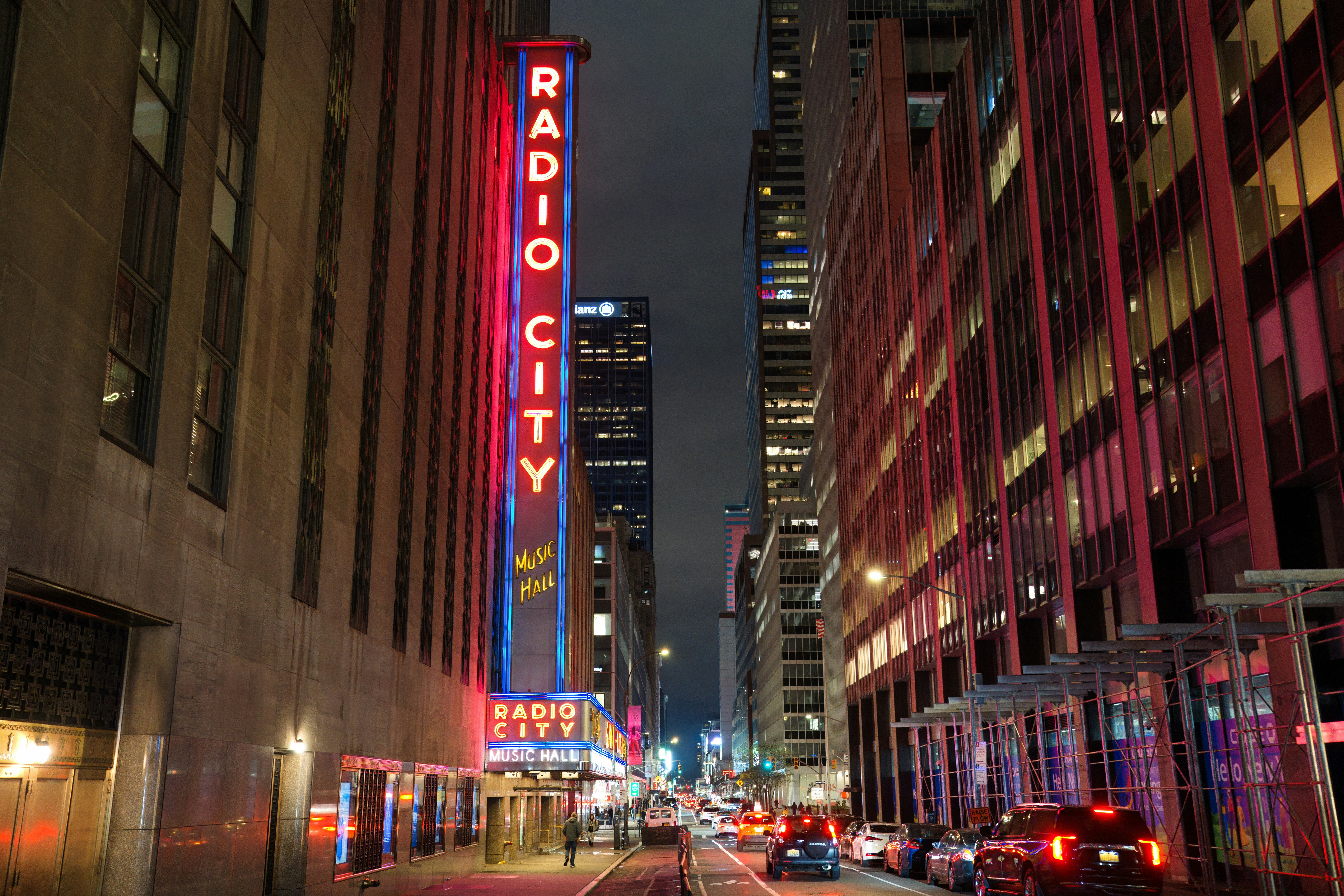 a city street at night with a radio city sign lit up
