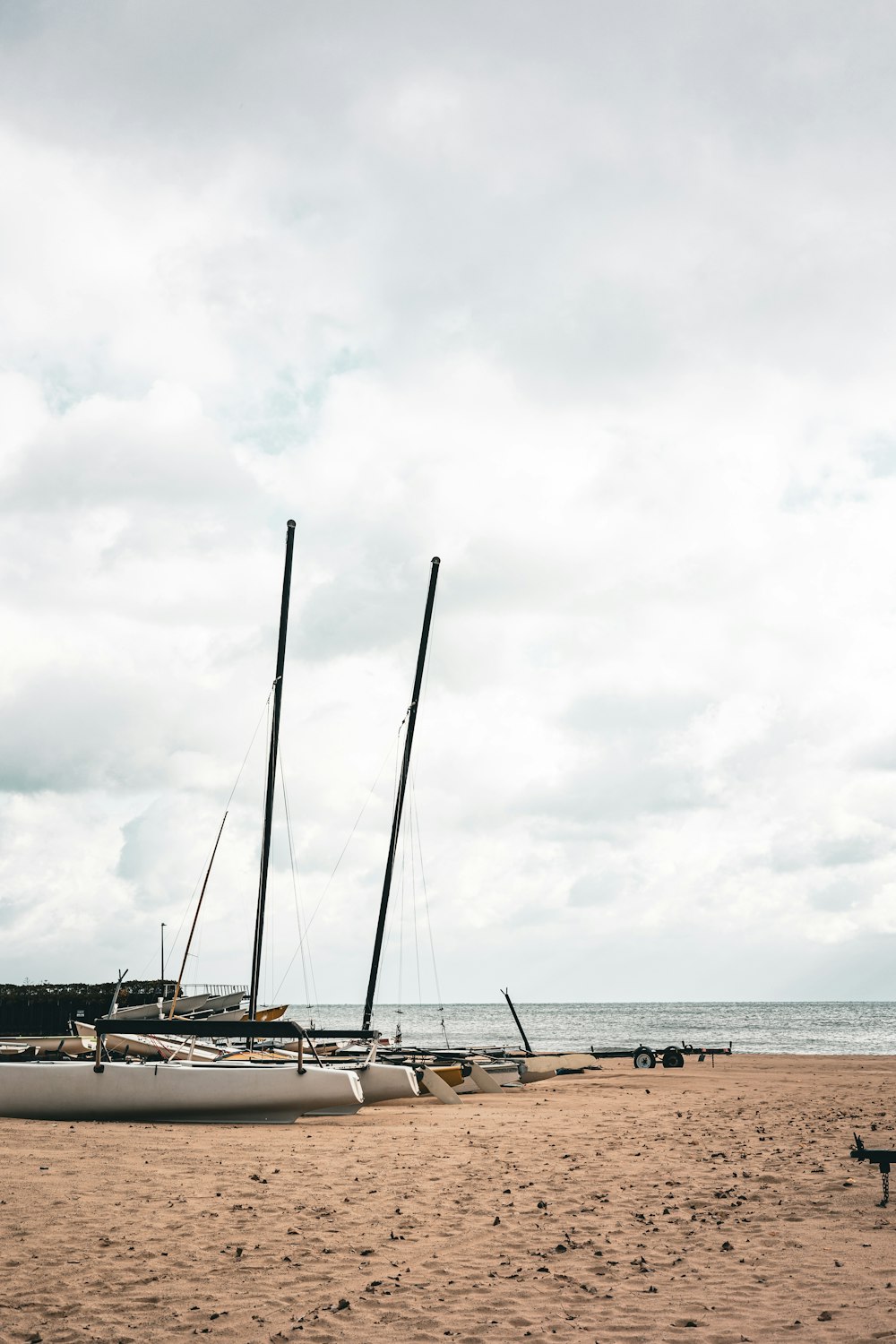 a couple of sail boats sitting on top of a sandy beach