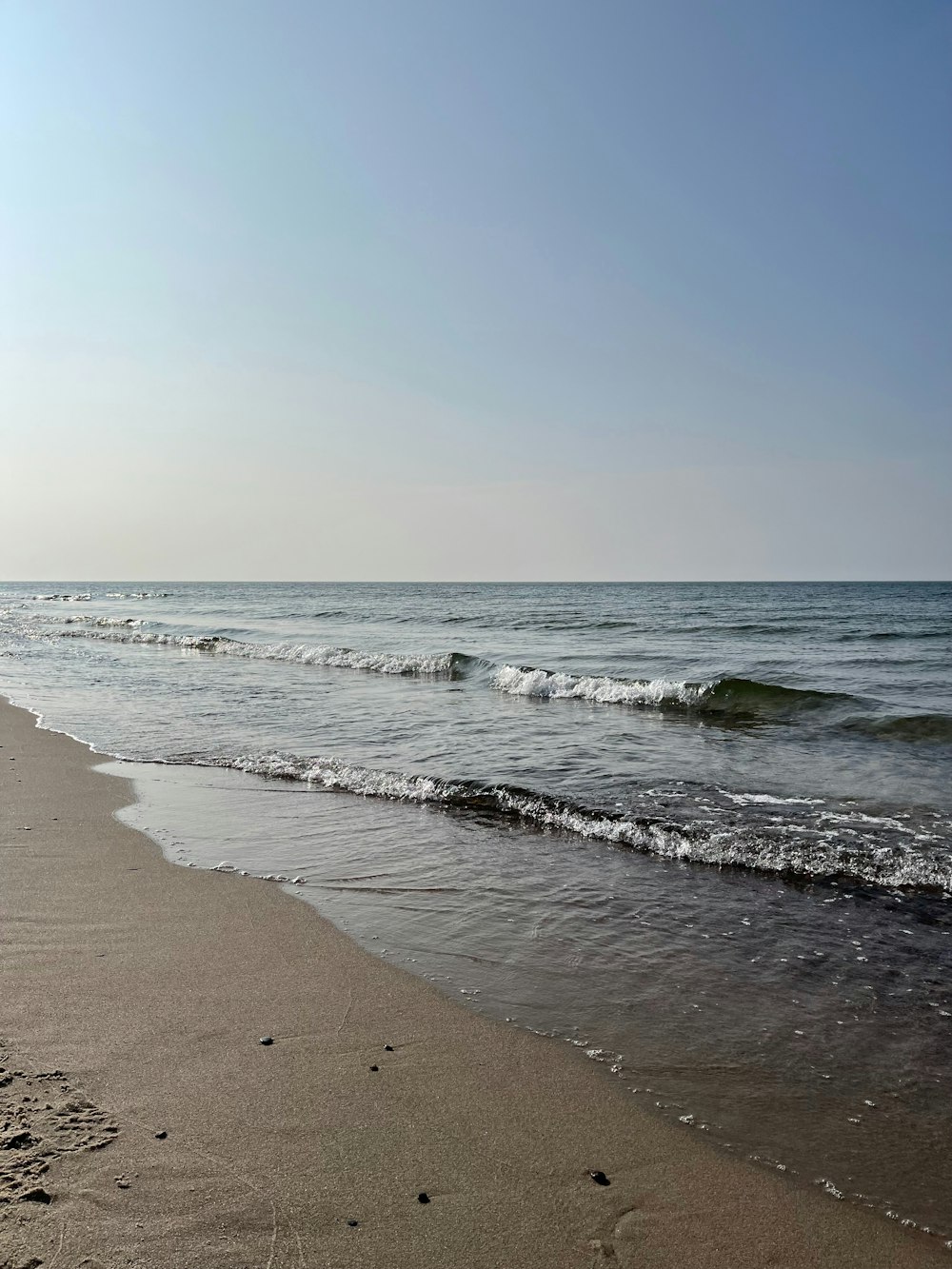 a sandy beach with waves coming in to shore