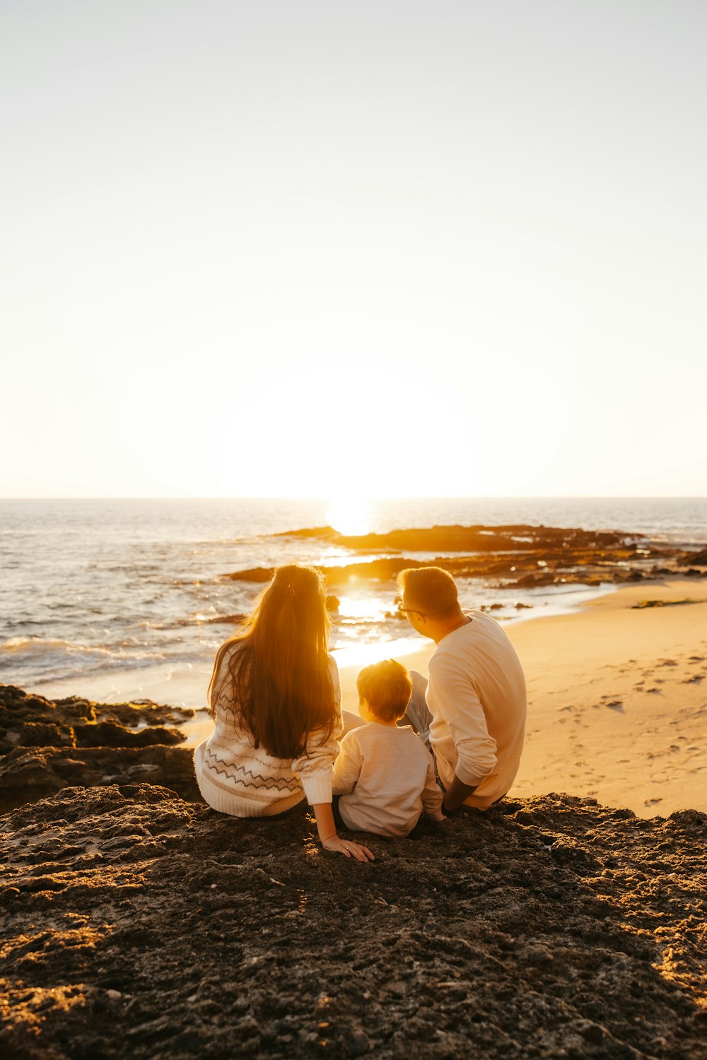 a family sitting on the beach at sunset