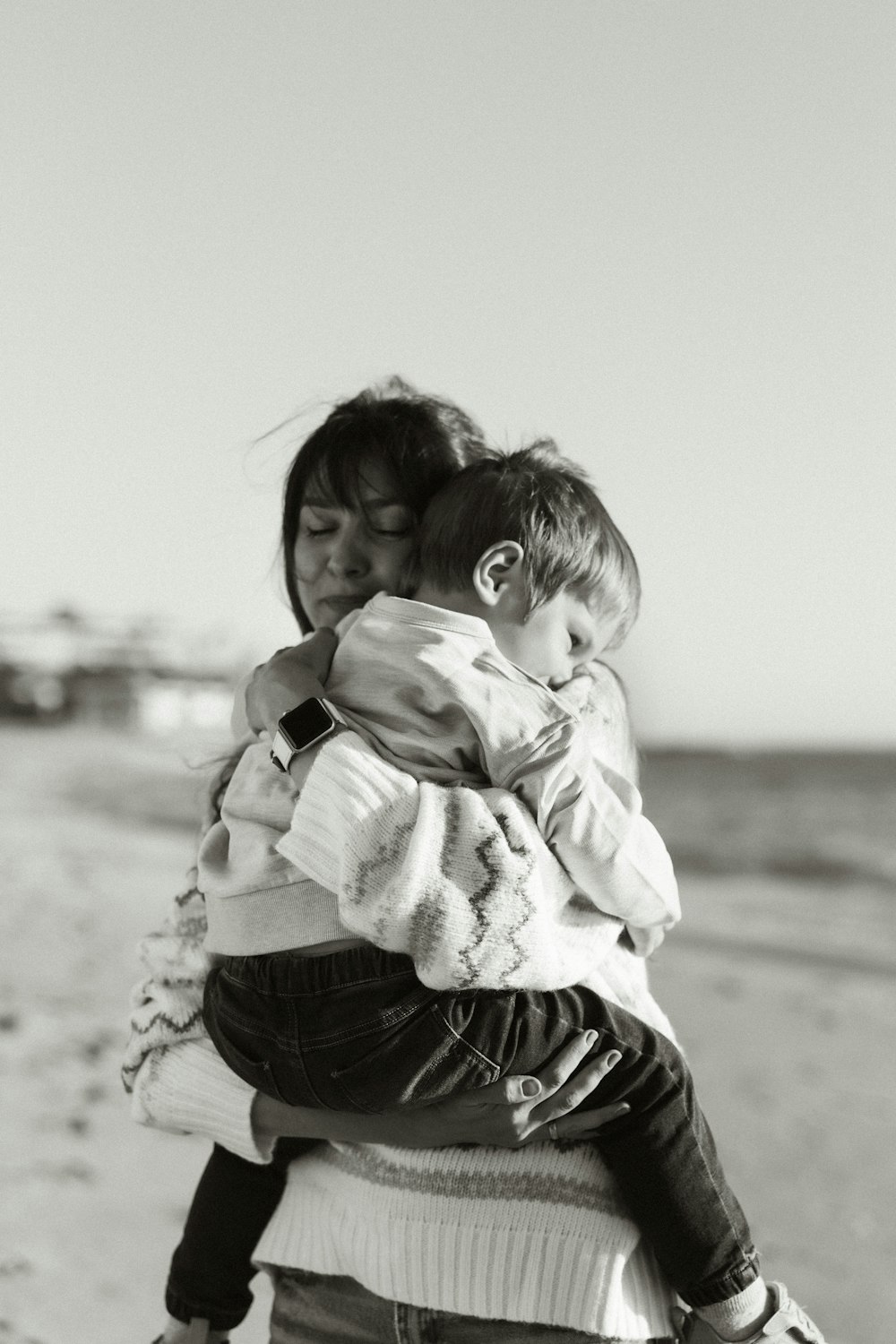 a woman carrying a child on the beach