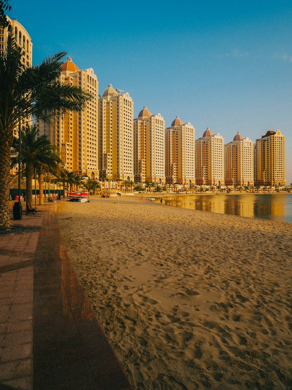 una spiaggia sabbiosa accanto ad alti edifici e palme