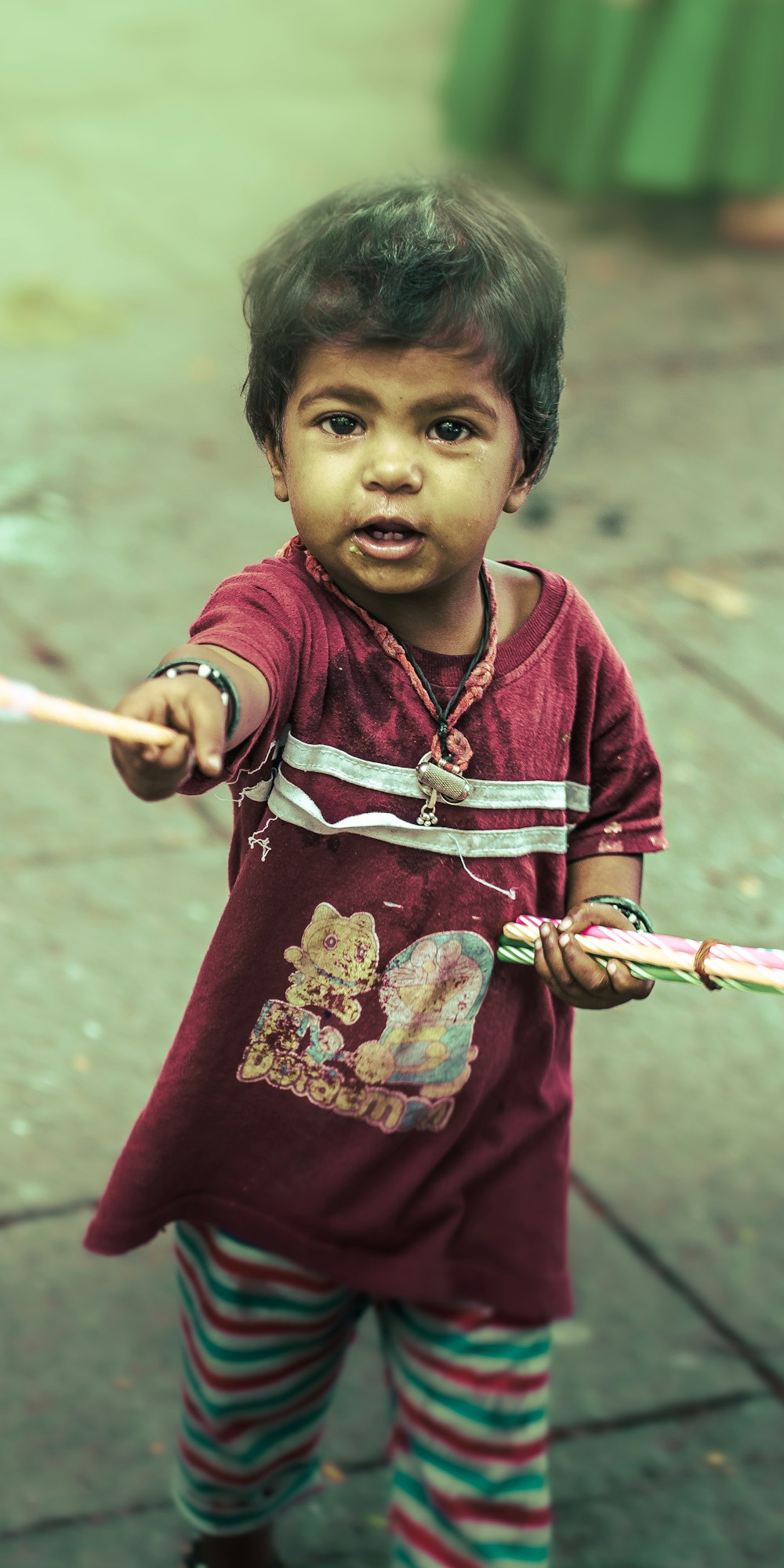 a little boy holding a stick and wearing a red shirt