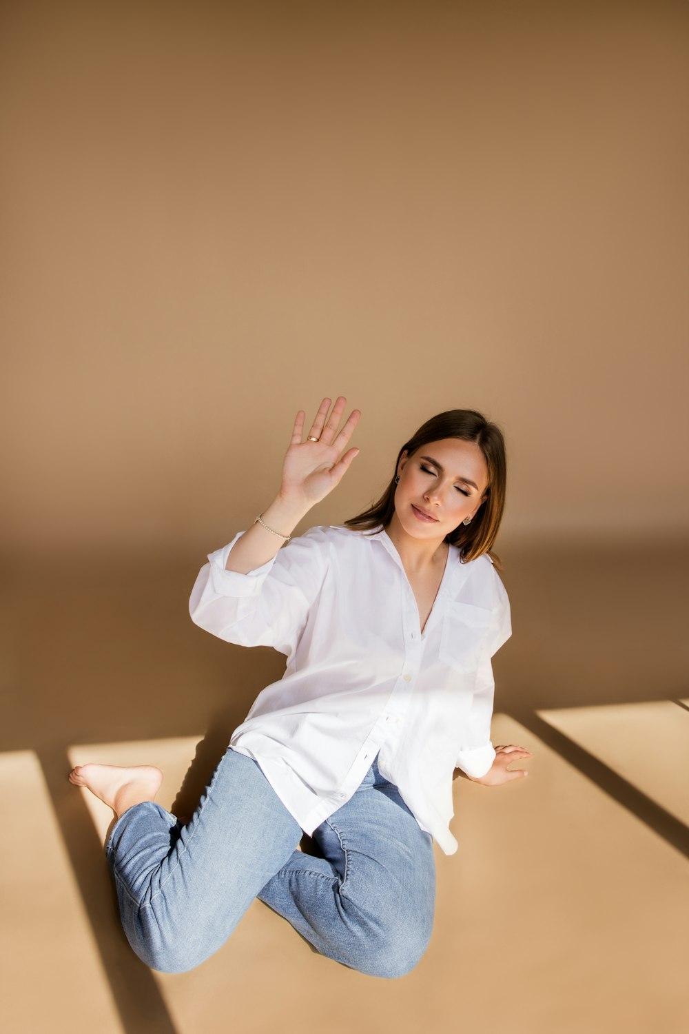 a woman is sitting on the floor with her hands in the air