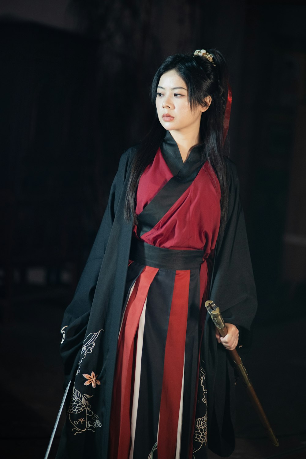 a woman in a black and red dress holding a sword