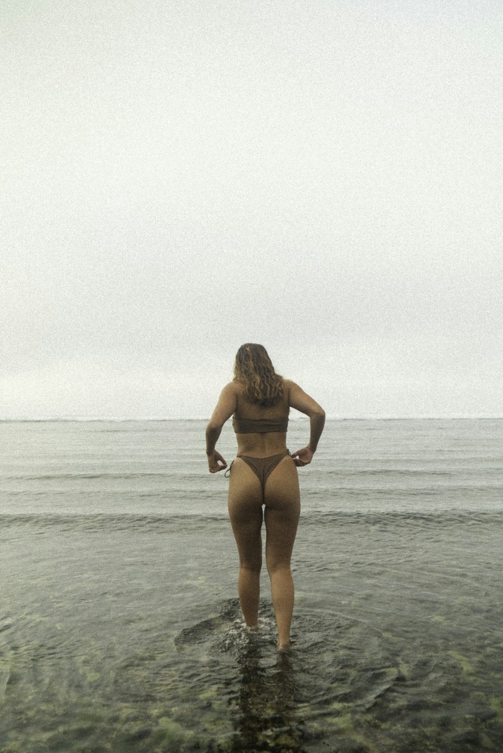 a woman standing in the water looking at the ocean