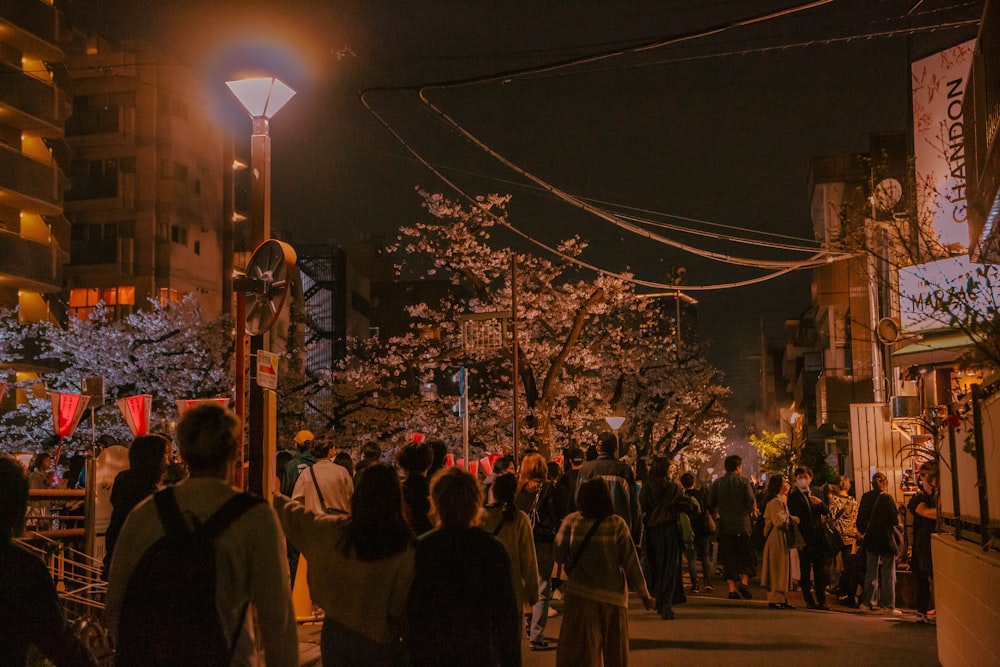 uma multidão de pessoas caminhando por uma rua à noite