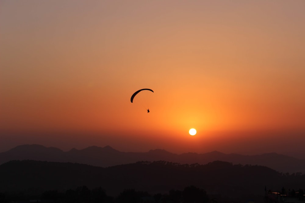 a couple of kites flying in the sky at sunset