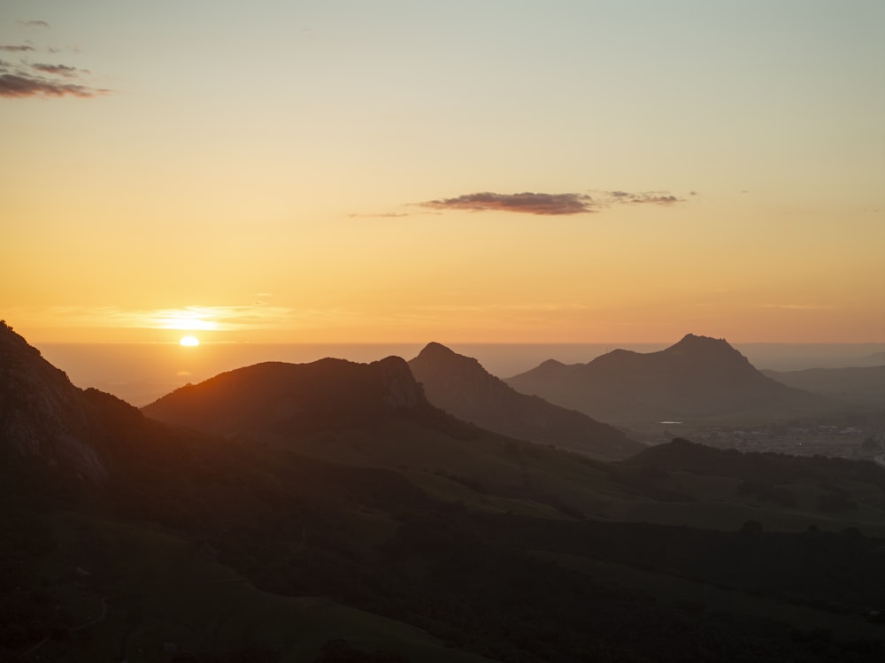 the sun is setting over a mountain range