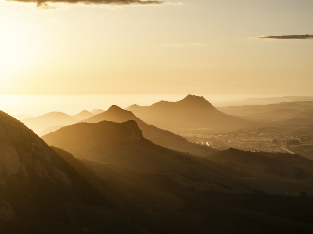 una persona che si leva in piedi sulla cima di una montagna al tramonto