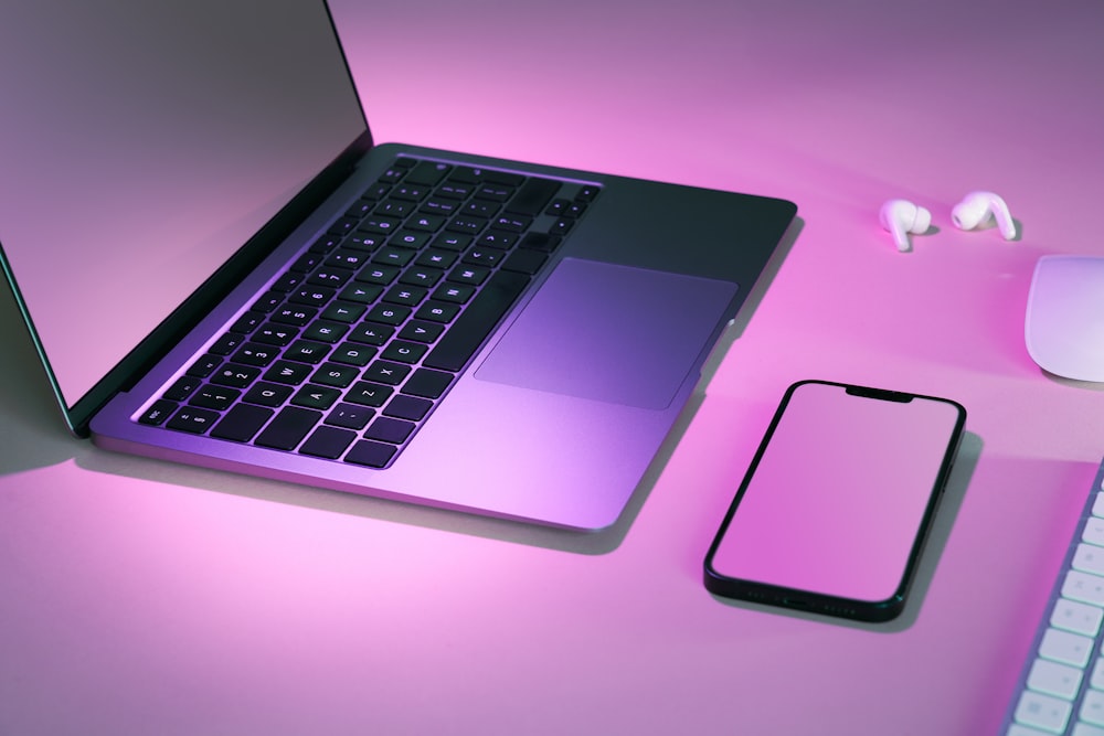 a laptop computer sitting on top of a desk next to a phone