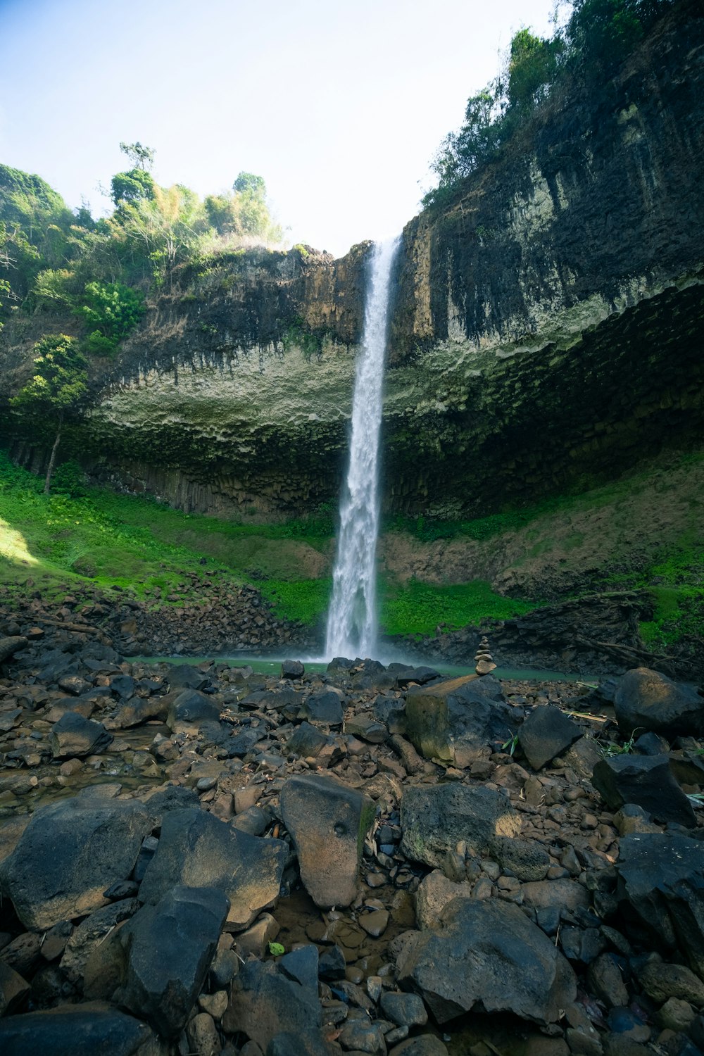 a very tall waterfall in the middle of a rocky area