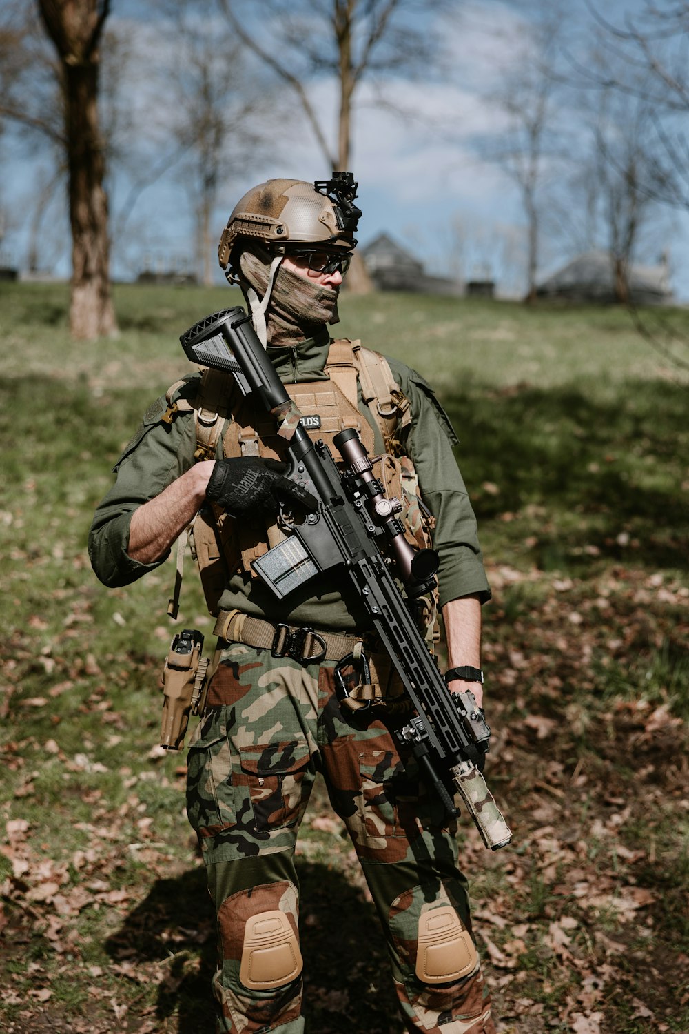 a man in camouflage holding a rifle in a field