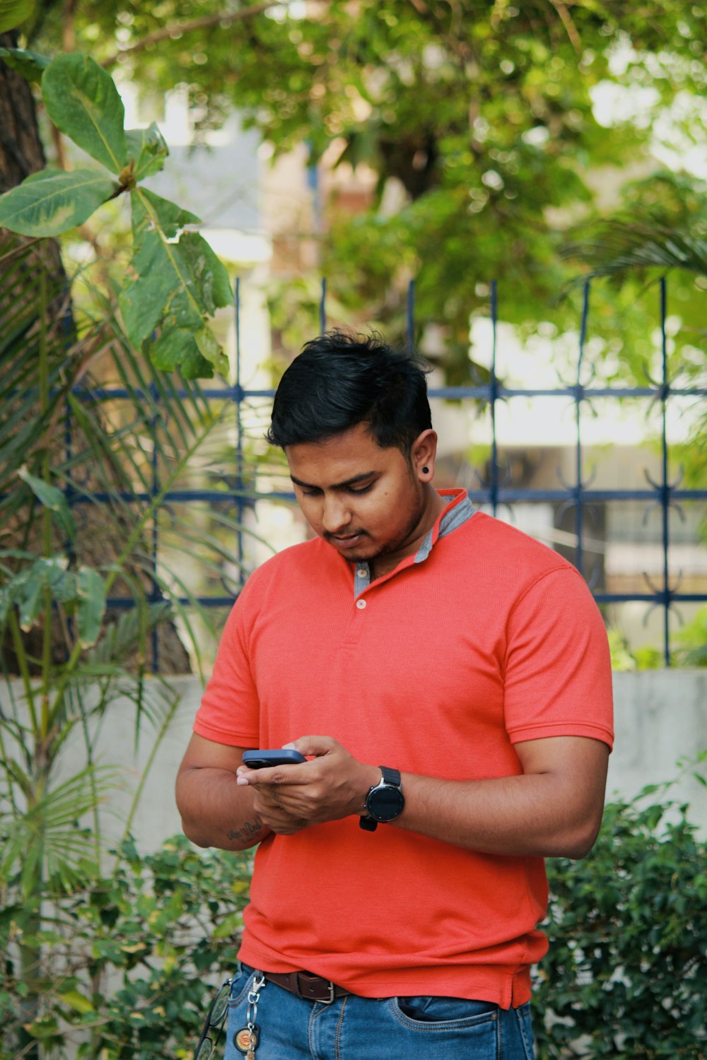 a man in a red shirt looking at his cell phone