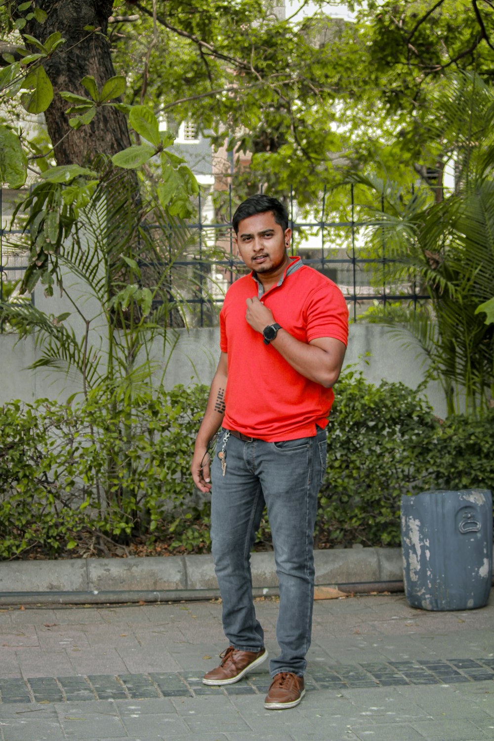 a man in a red shirt standing on a sidewalk