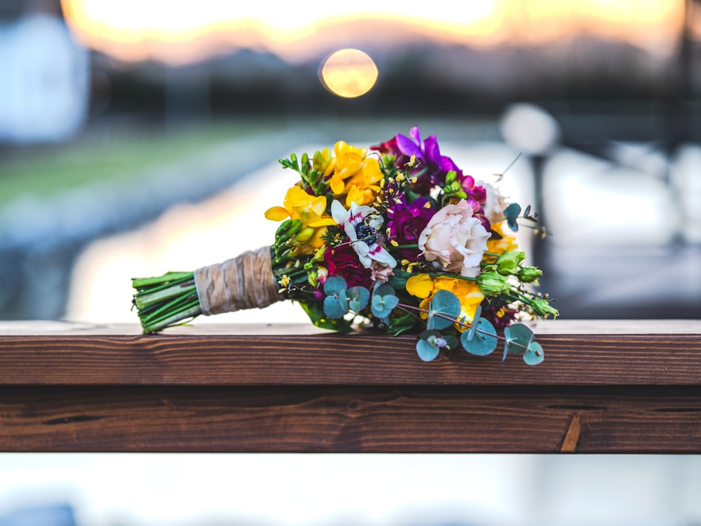 a bouquet of flowers sitting on top of a wooden rail