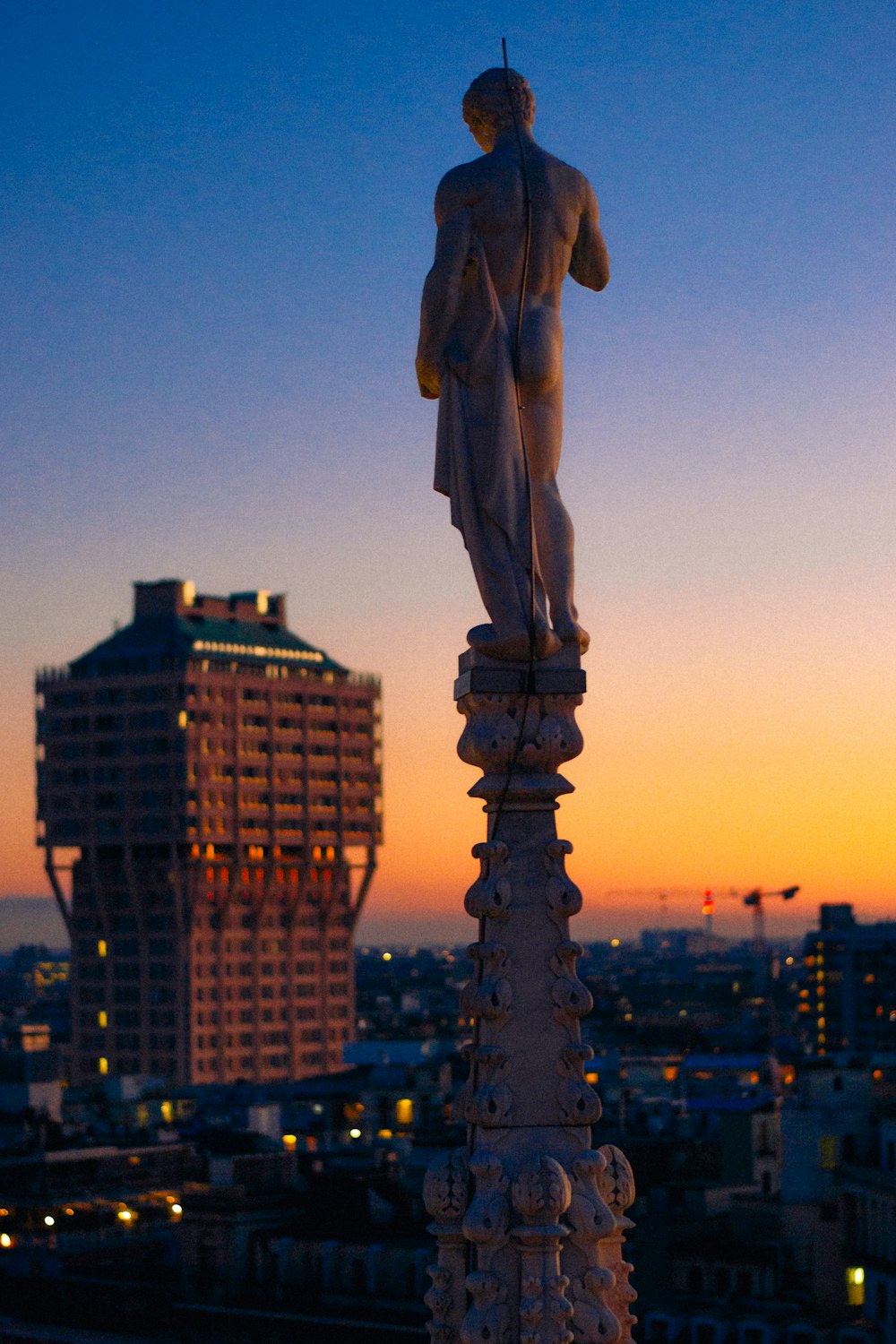 a statue on top of a building with a city in the background