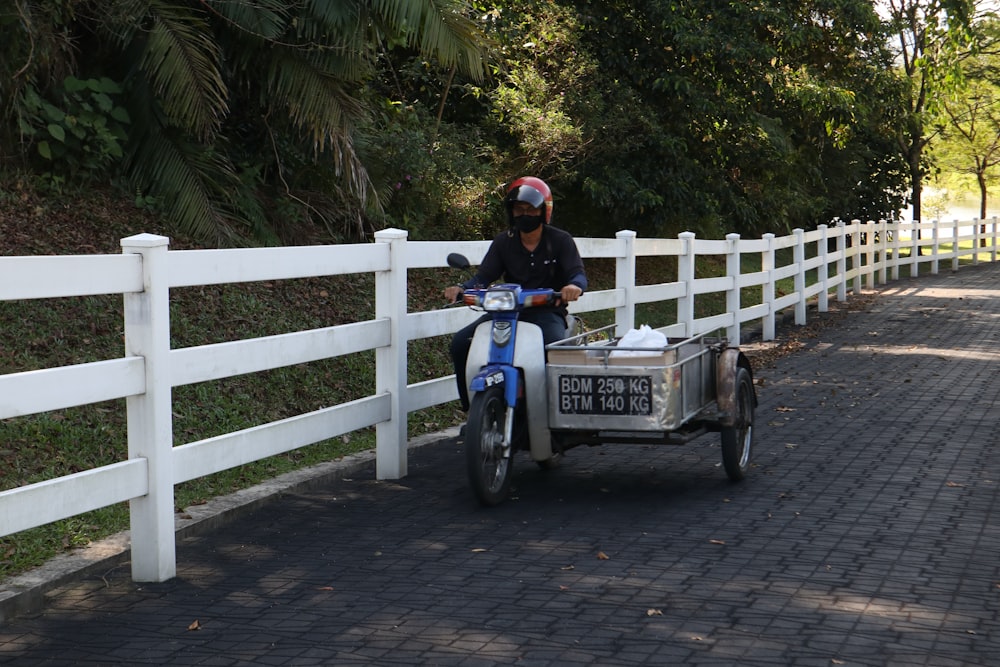 un homme conduisant une motocyclette à laquelle est attachée une remorque ;