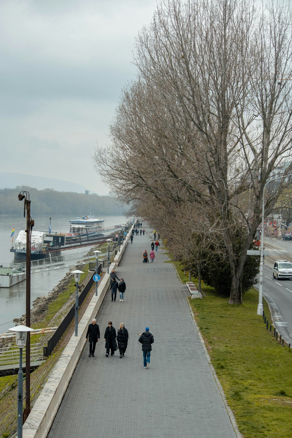 a group of people walking down a sidewalk next to a river