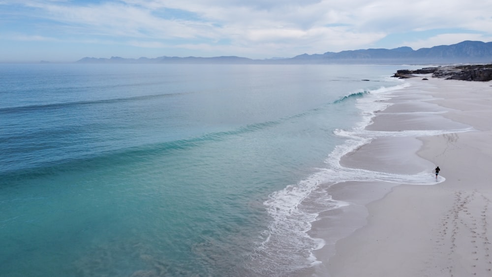 a person walking along a beach next to the ocean