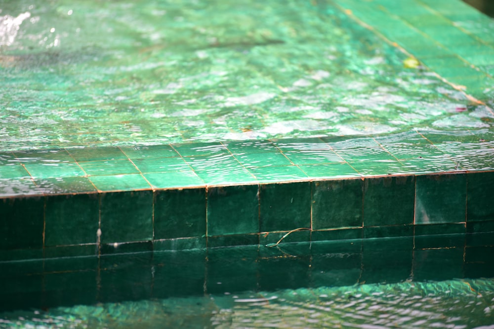 a close up of a pool with green tiles