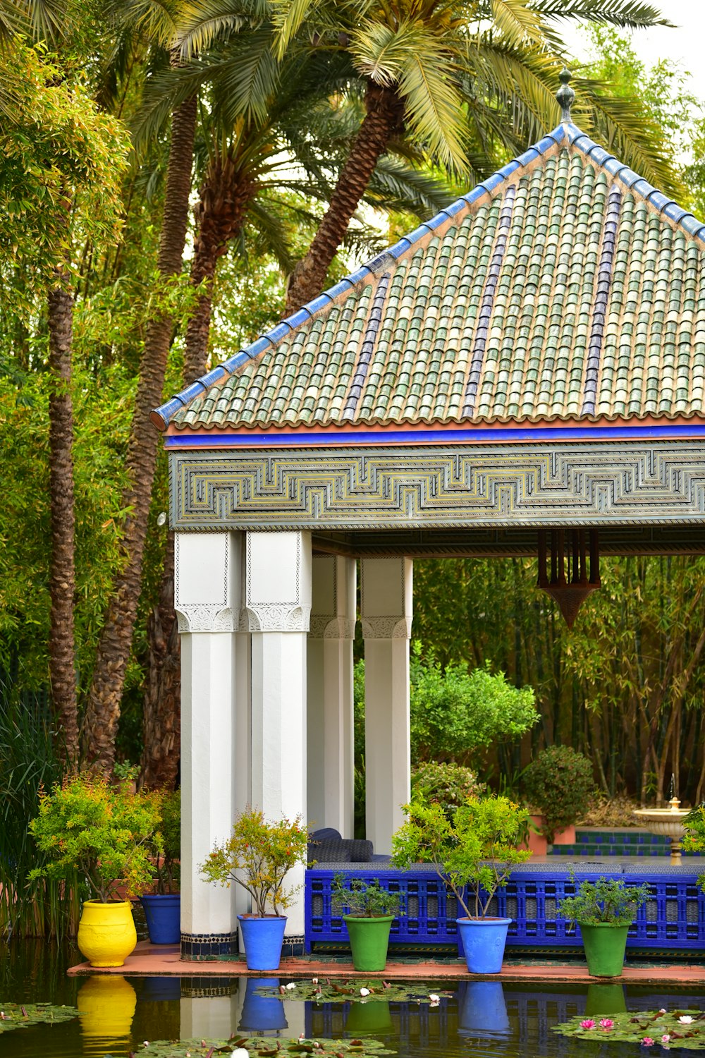 a gazebo in a garden with water lilies and palm trees