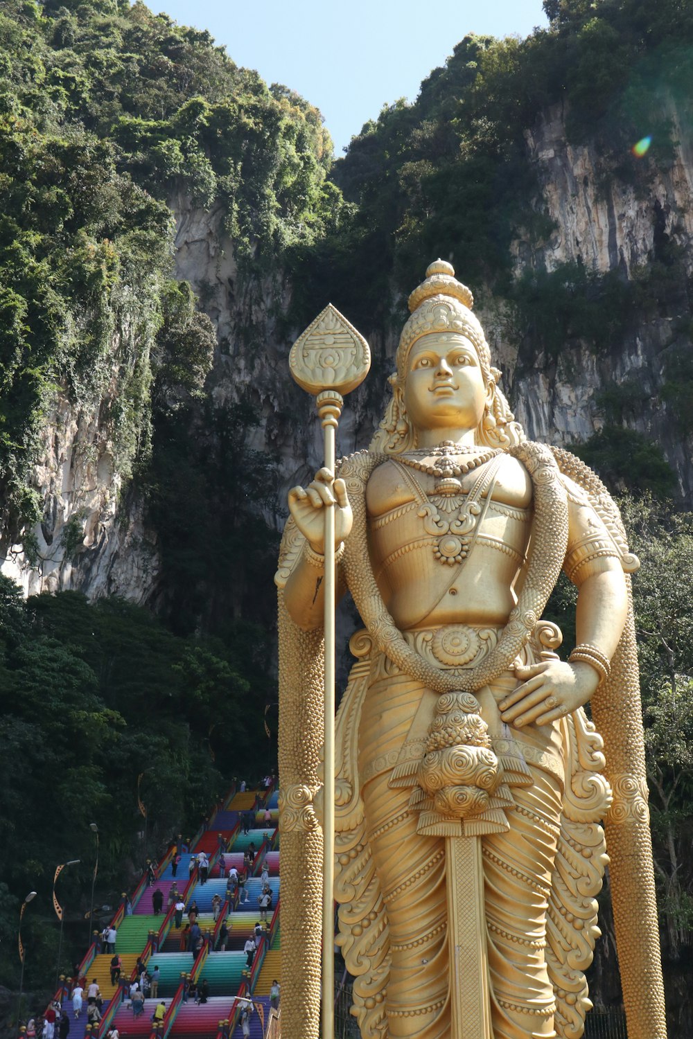 a statue of a man holding a spear in front of a mountain