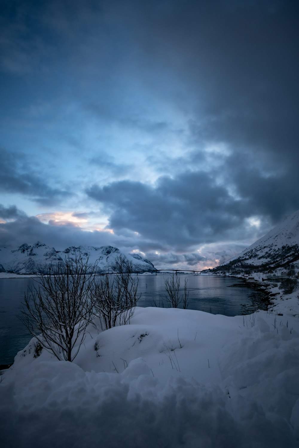 a snow covered field next to a body of water