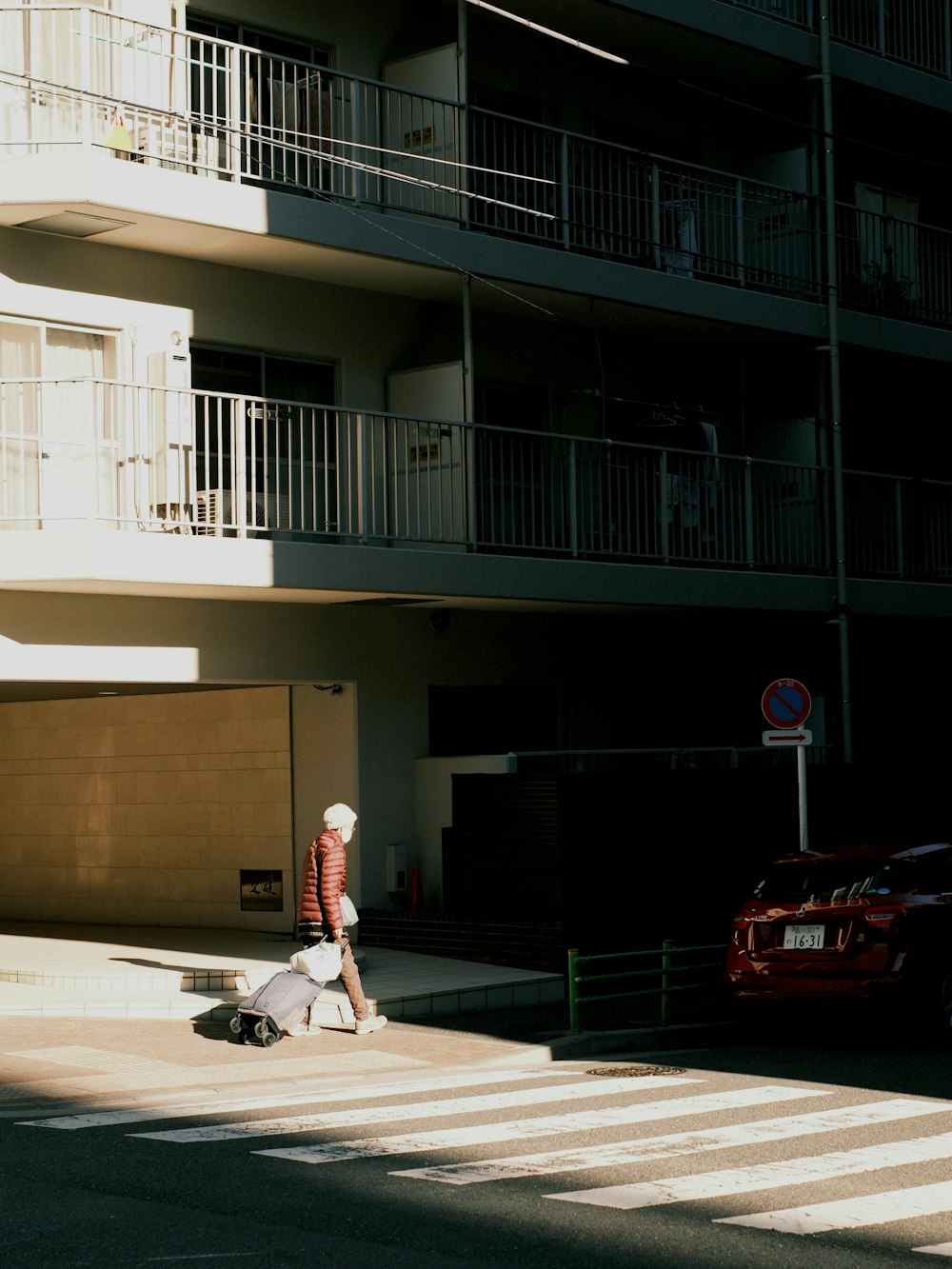 a person walking across a cross walk in front of a building