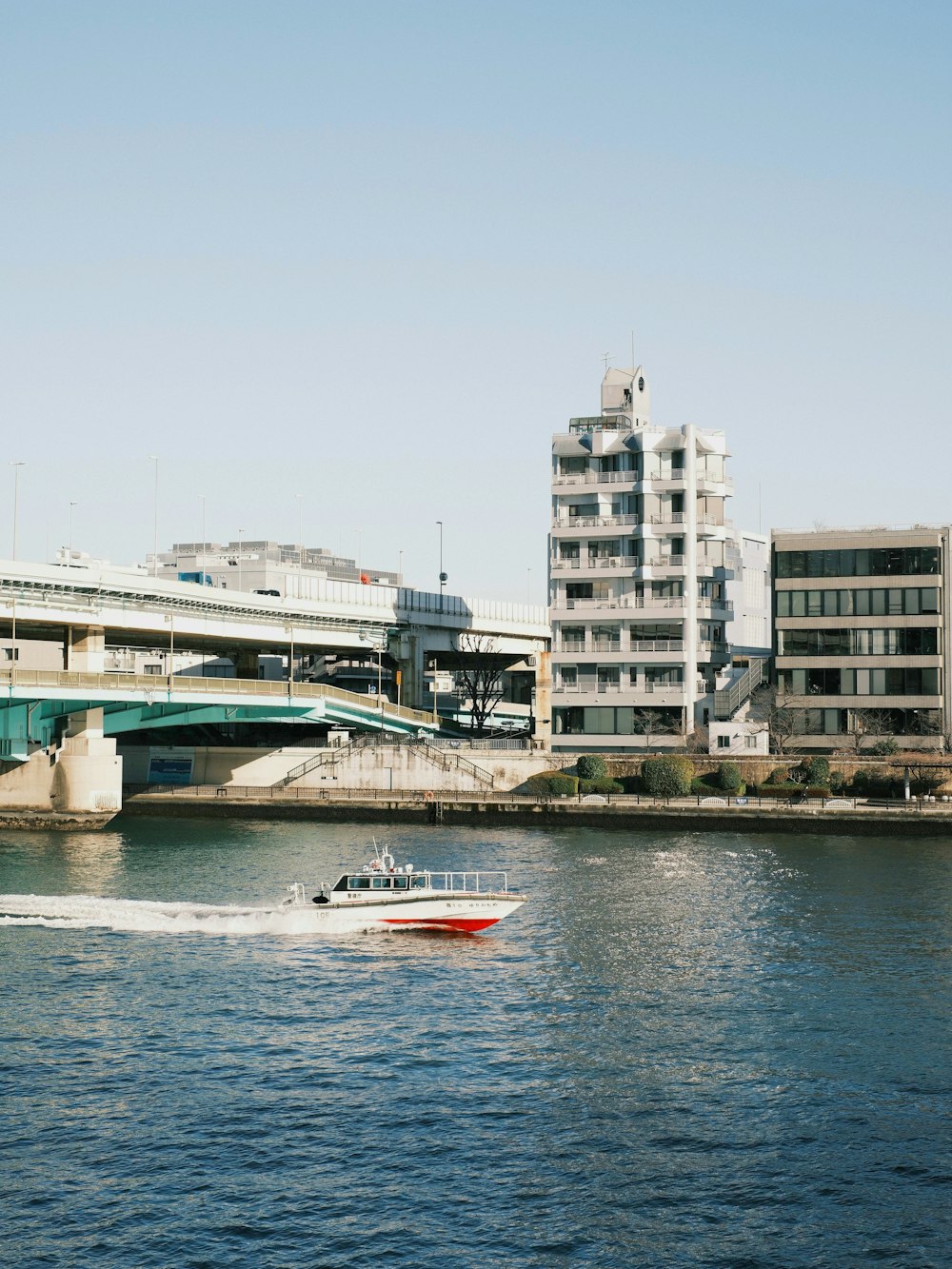 a boat traveling down a river next to a bridge